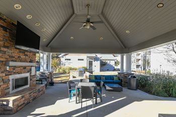 Outdoor fireside lounge with tv, soft seating, and grills